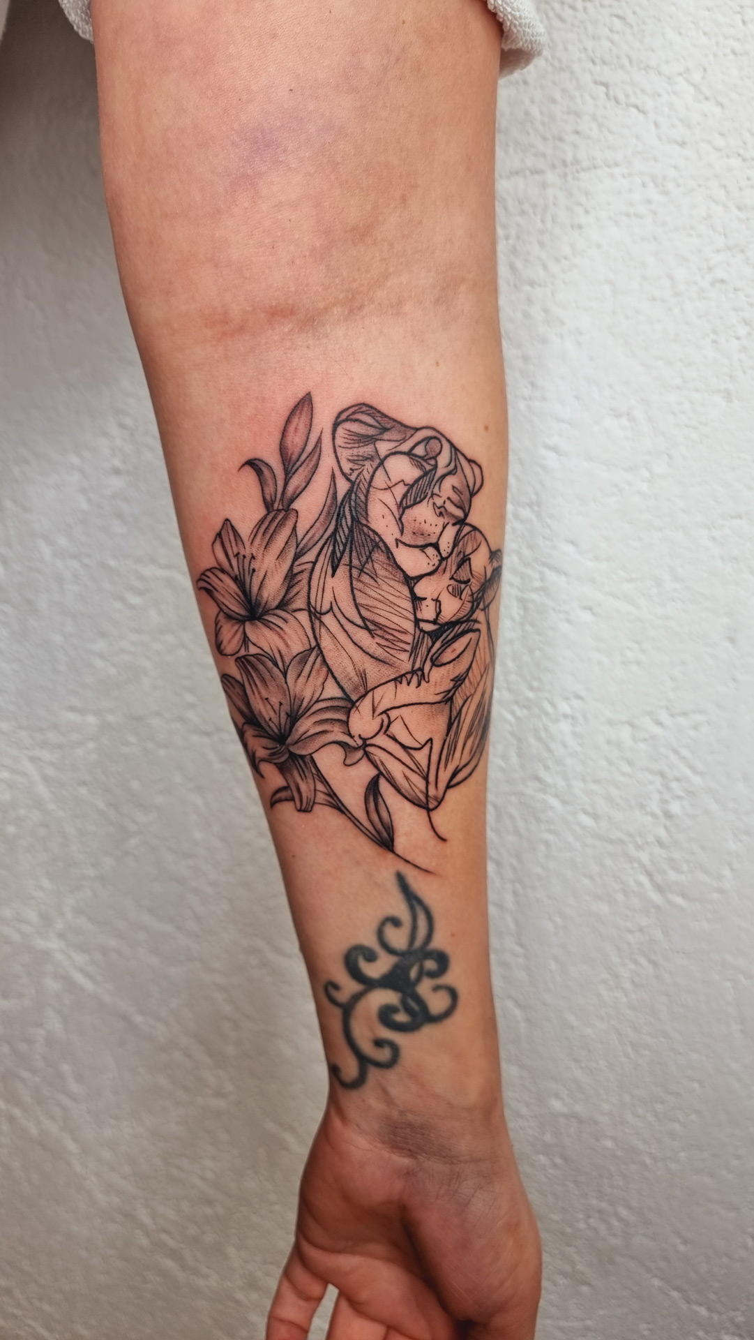 Unterarm mit ruhigem Ausdruck, schwarzes Linien Tattoo von Mutter und Kind mit Blumen