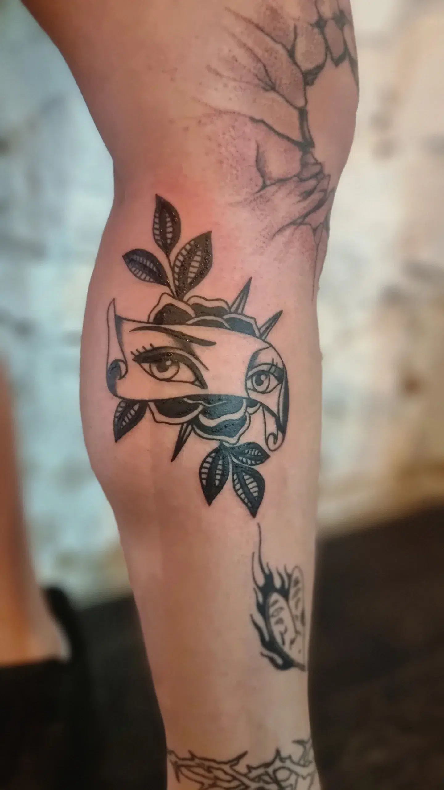 Unterarm mit neutralem Tattoo Auge in blauer Rose und schwarzen Blattern
