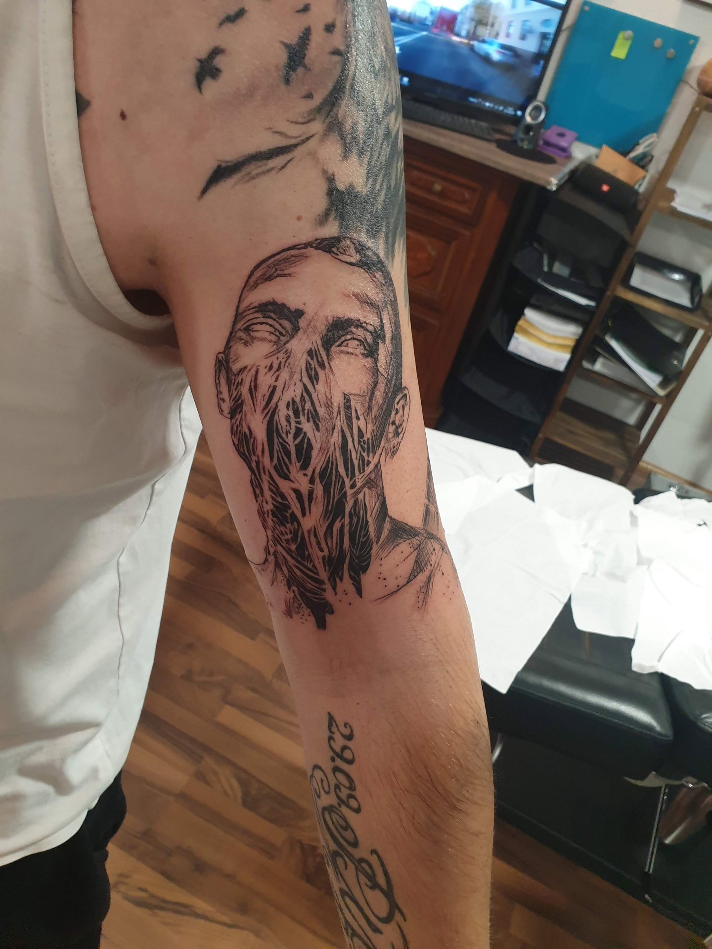 Person mit neutralem Blick, Arm mit schwarzem Barttattoo und Muster
