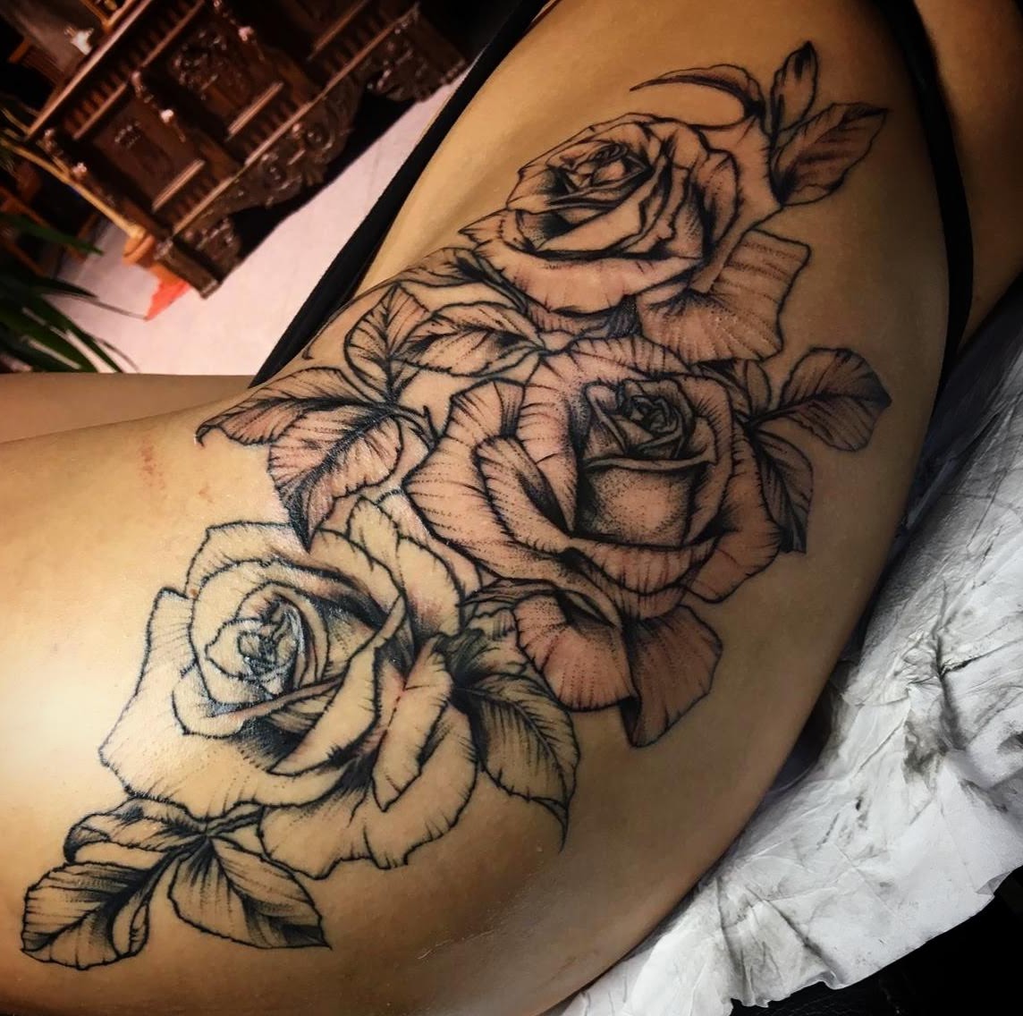 Bein mit ruhiger Haut und schwarzem Rosen Tattoo mit drei Blüten