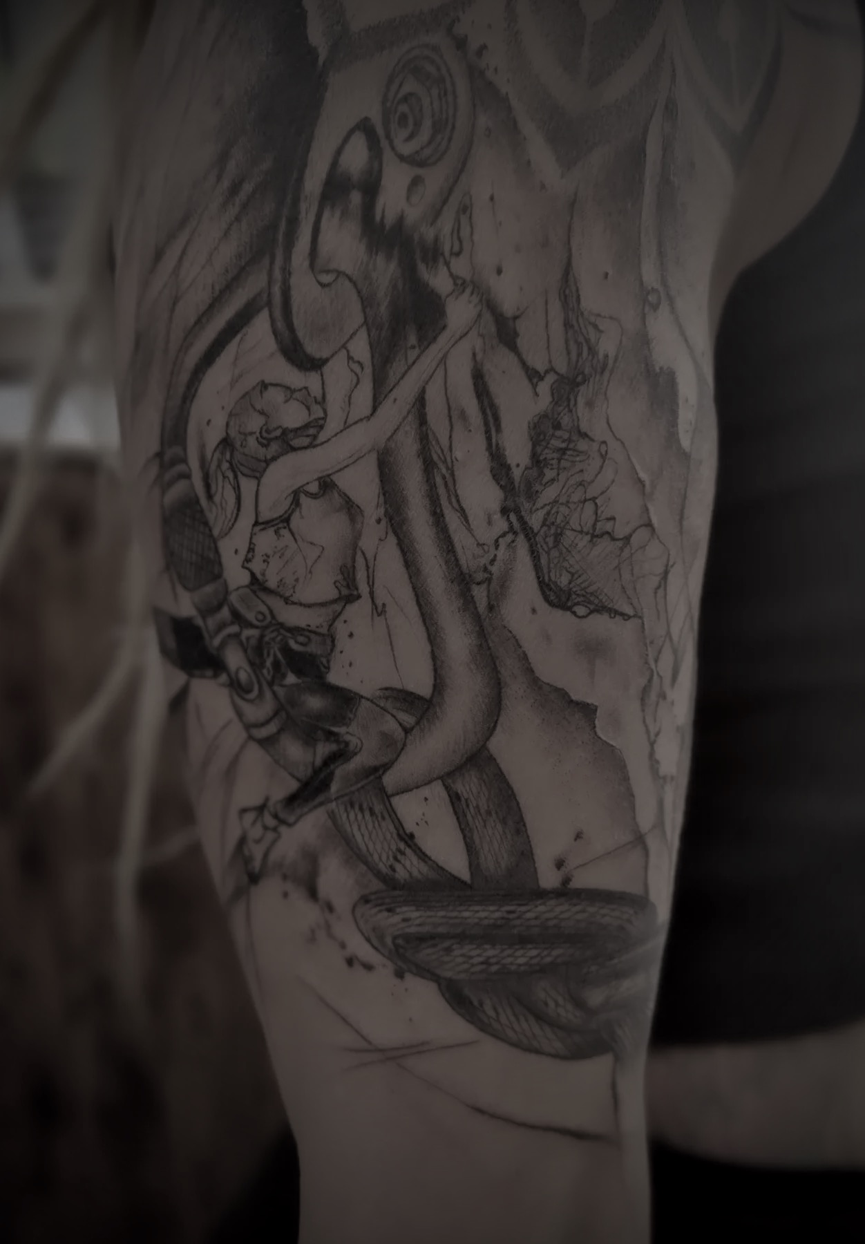 Abstraktes Schwarz Grau Tattoo mit Schlangen und Spiralen auf einem Arm