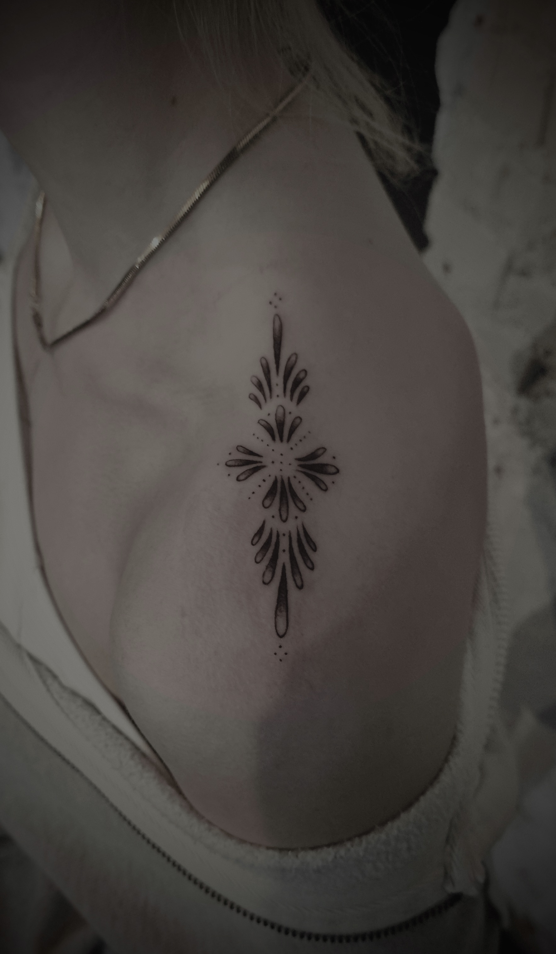 Filigranes Ornament Tattoo in Schwarz auf der Schulter einer Person