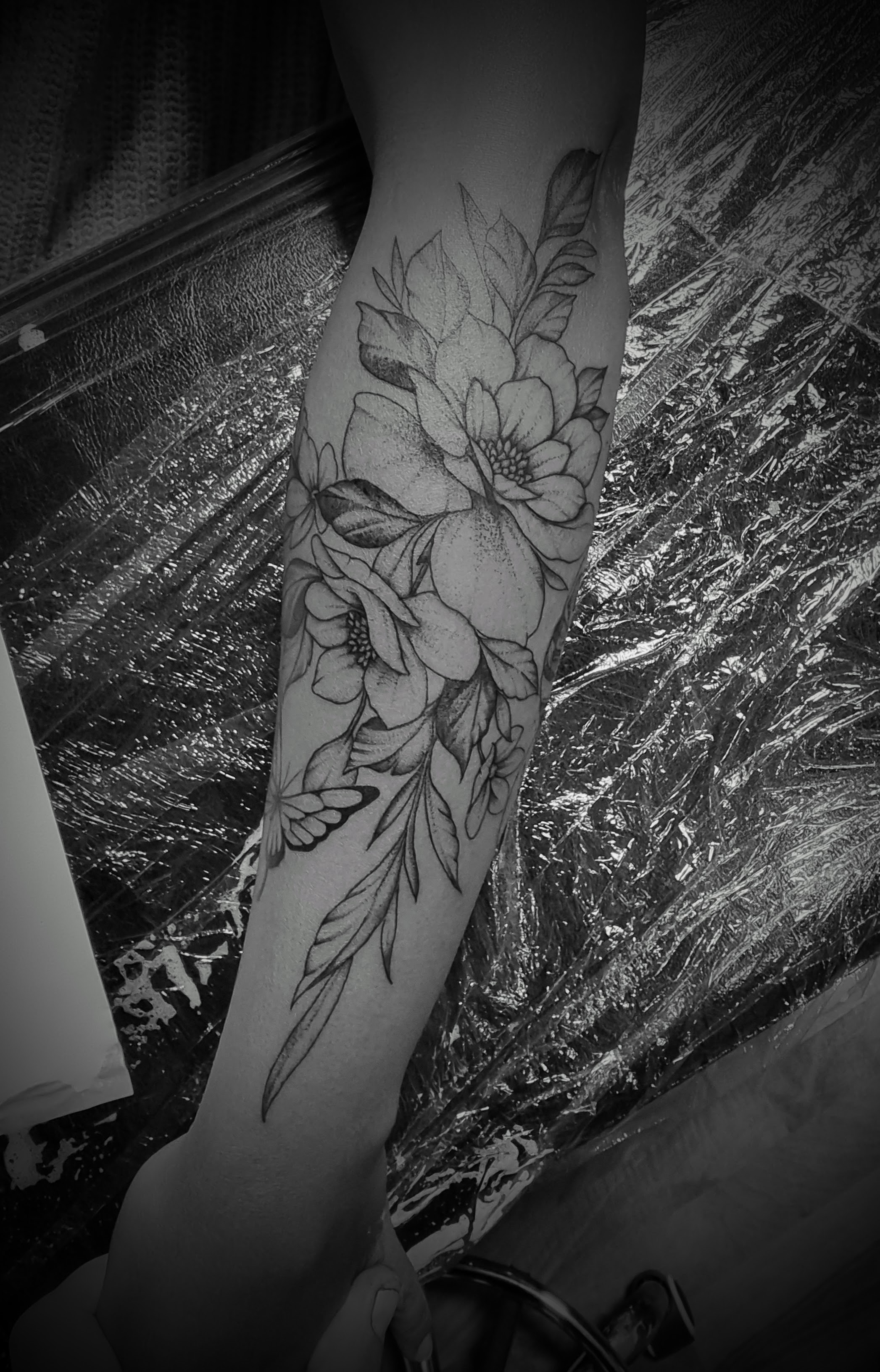 Schwarzweiss Foto eines Unterarms mit filigranem Blumen Tattoo