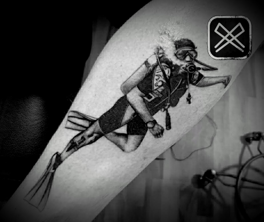 Schwarzweisses Tattoo eines Tauchers mit Ausruestung auf einem Arm
